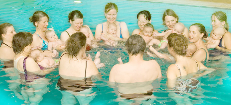Mütter im Kreis mit Kindern im Wasser: behutsame und angstfreie Hinführung zum Wasser durch Babyschwimmen